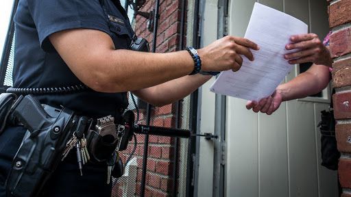 A police officer is handing a piece of paper to a person.