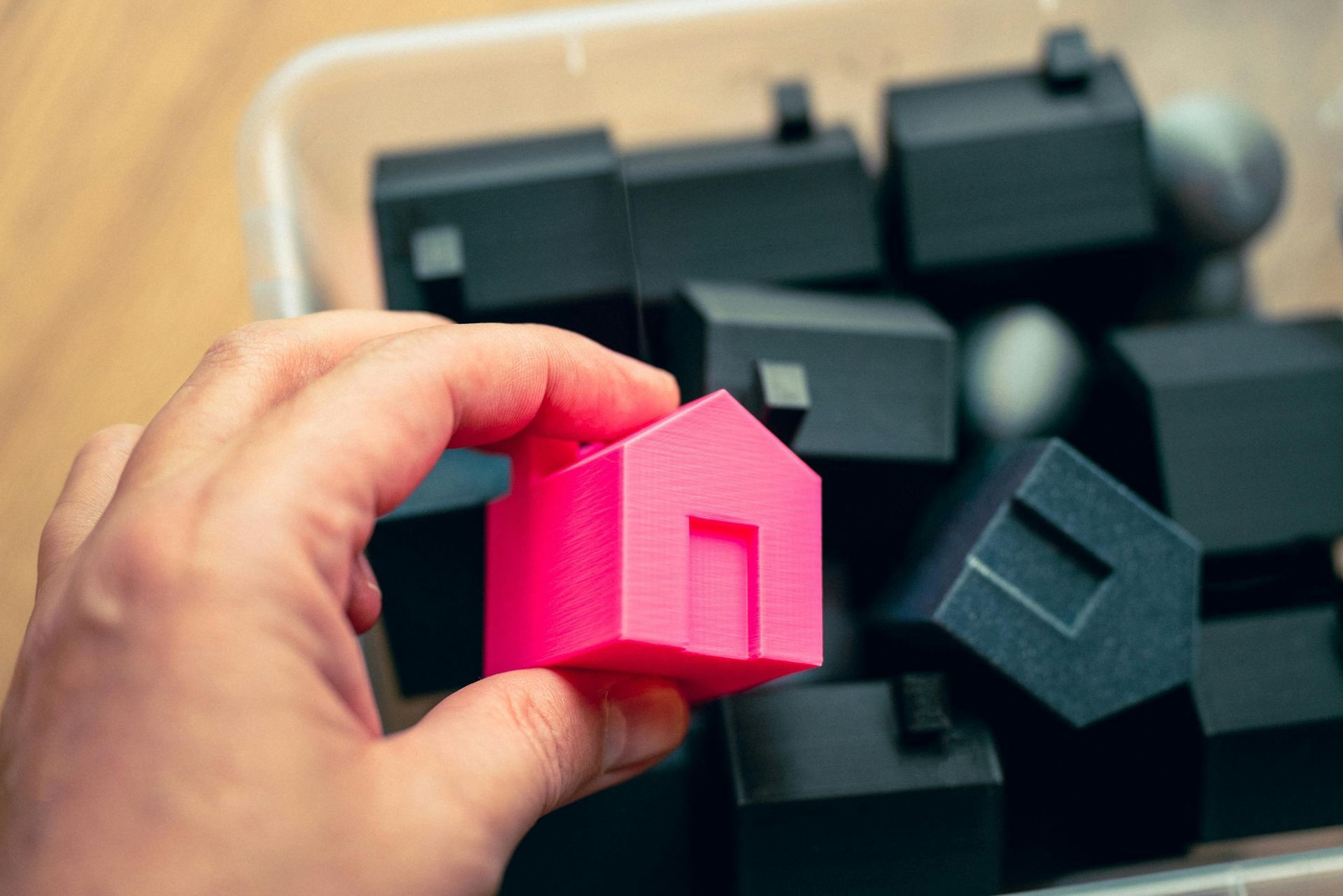 A person is holding a pink toy house in their hand.