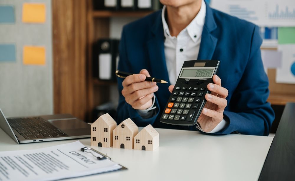 A man is sitting at a desk holding a calculator and a pen.