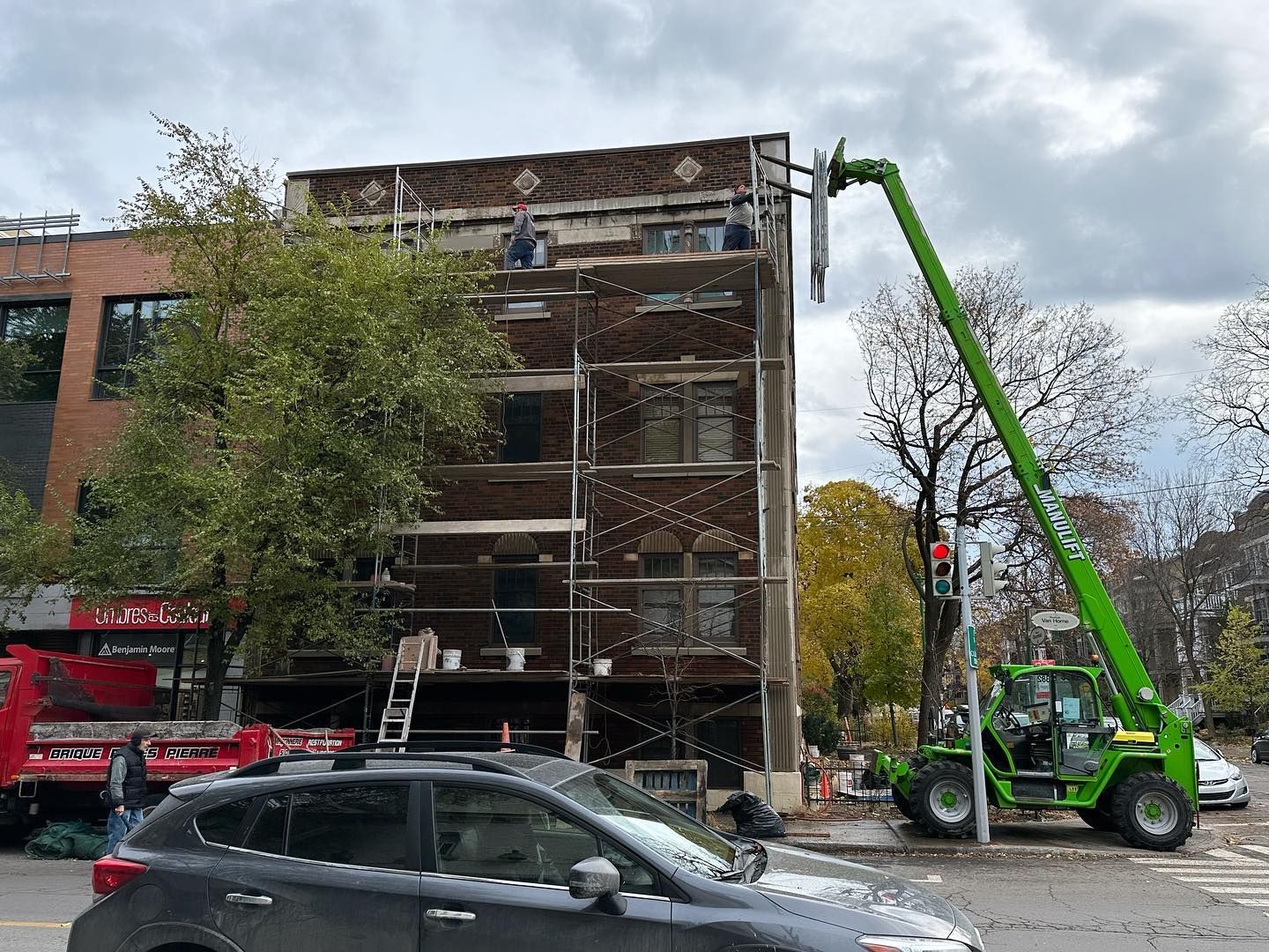 Façade du bâtiment en construction. Un grand ascenseur végétalisé dessert les étages supérieurs. L'échafaudage est en place.