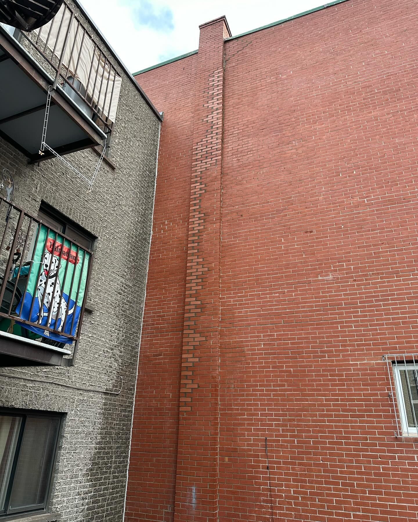 Vue extérieure de deux bâtiments en briques. L'un est rouge, l'autre gris, avec des balcons.