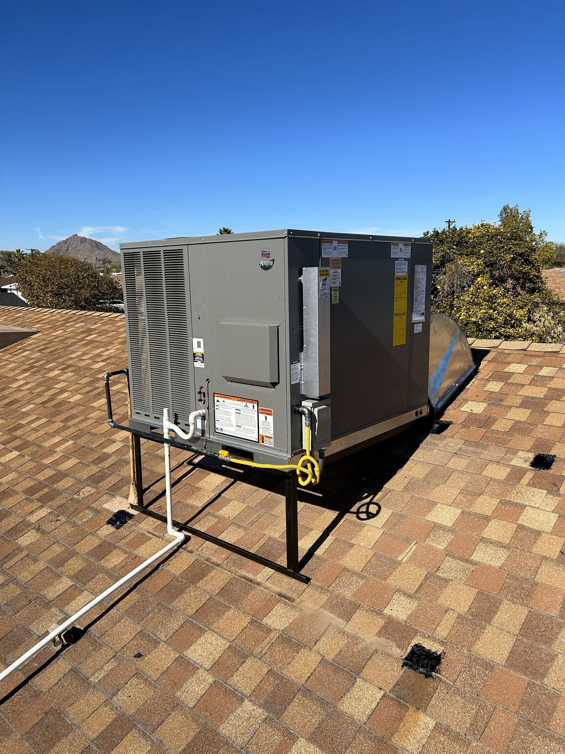 Rooftop HVAC unit on a brown tile roof against a clear blue sky.