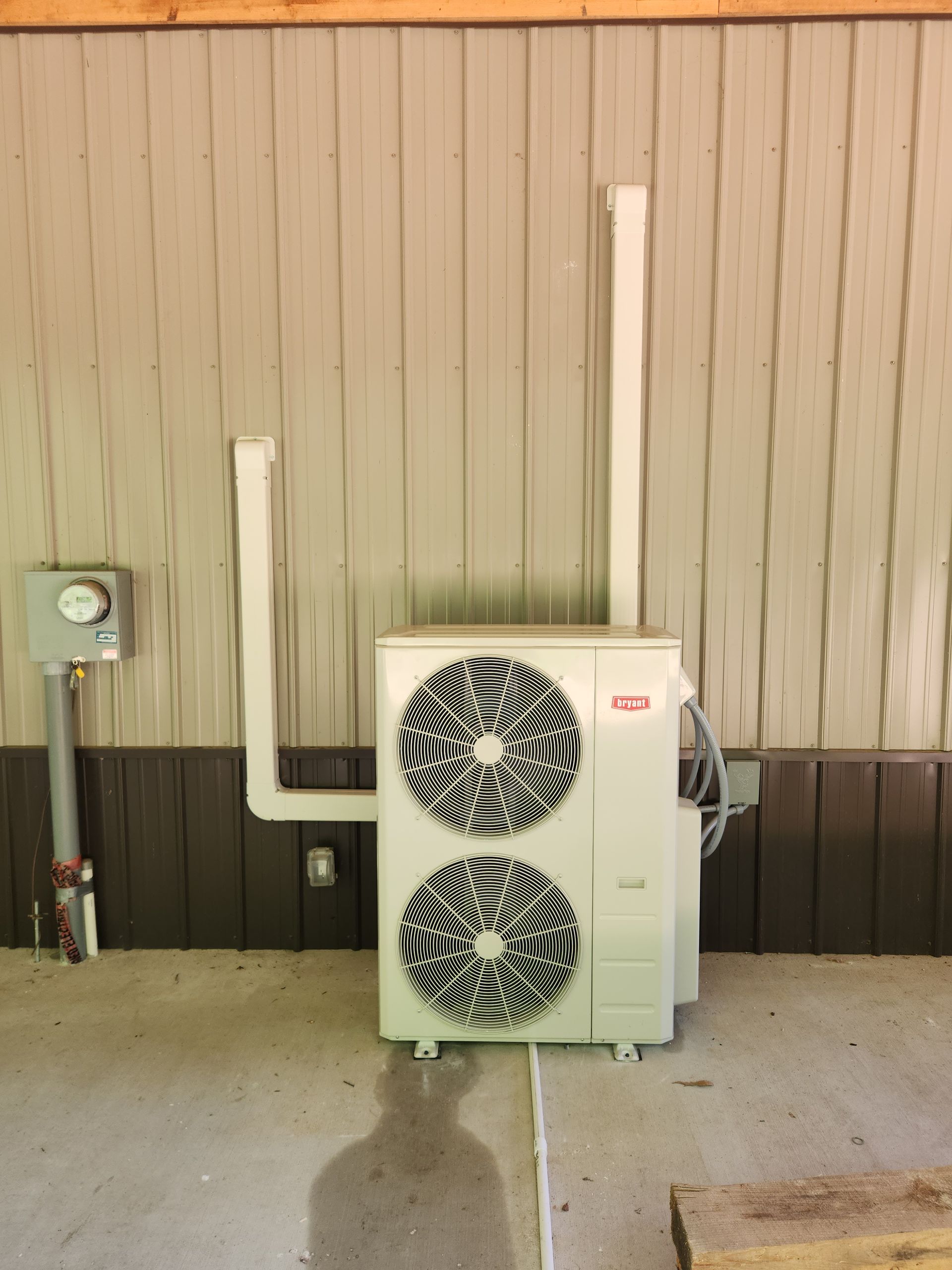 Outdoor heat pump unit with two fans and ventilation pipes on a building exterior.