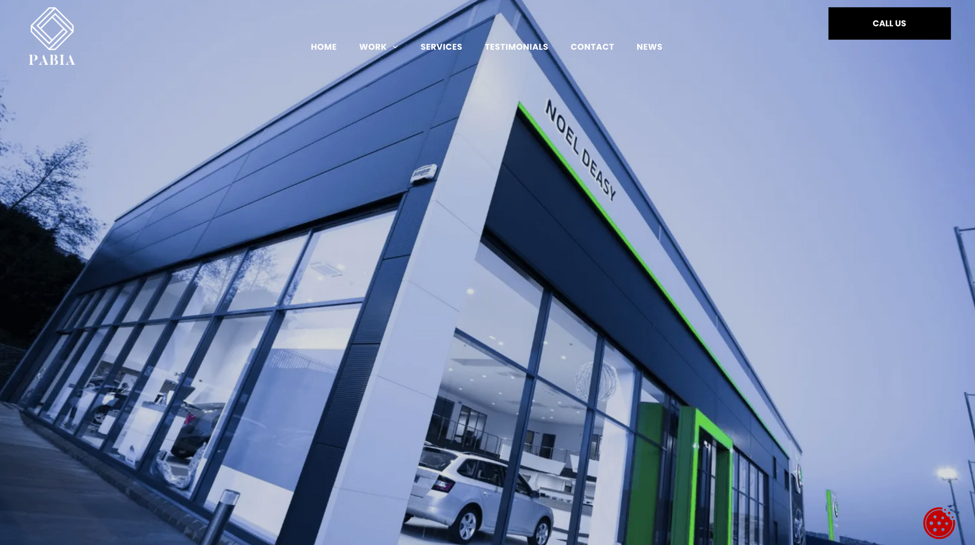 Modern building with large windows displaying cars inside, blue and green color accents.