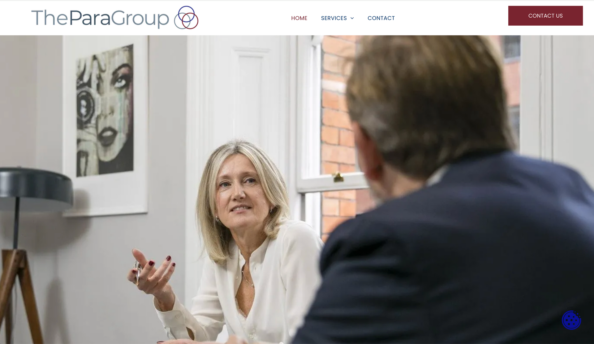 Woman gesturing in discussion with a man, seated at a table.
