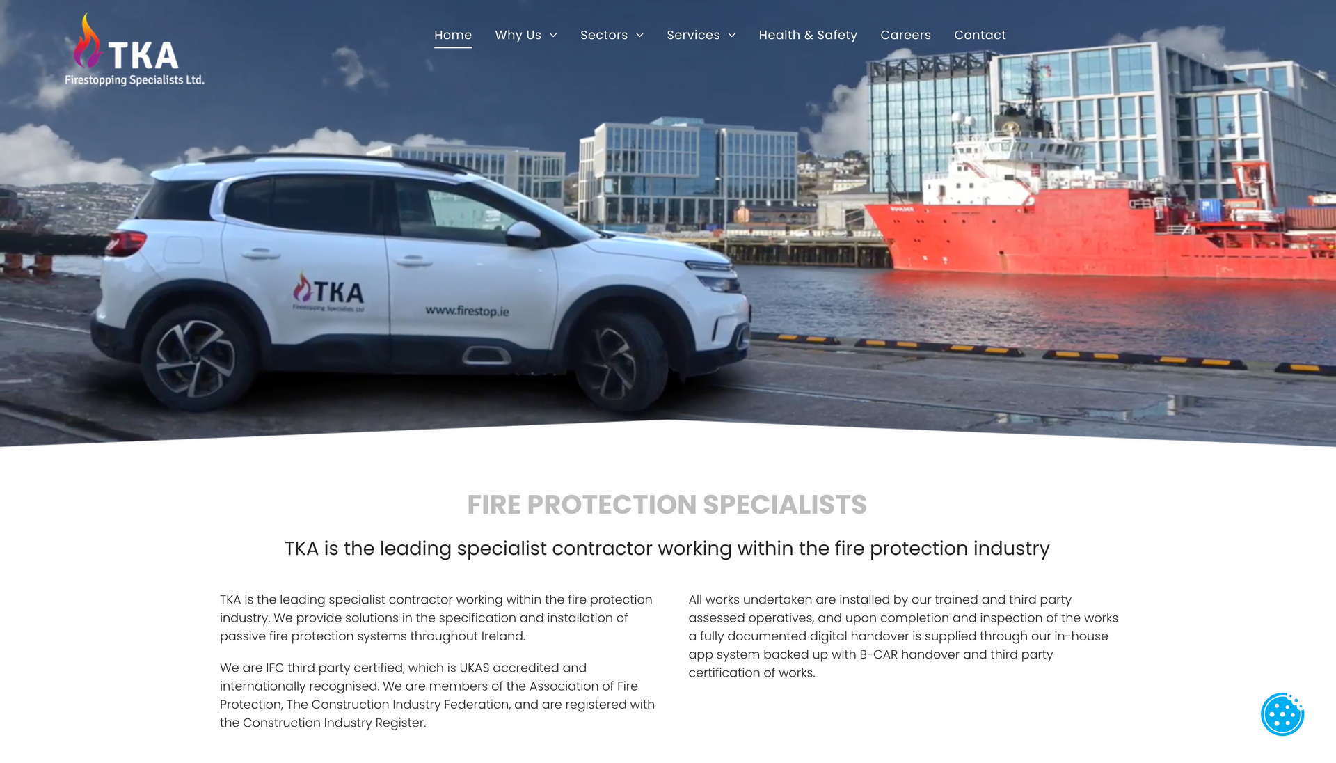 White SUV with TKA logo parked near a harbor, red ship in background; Fire protection specialists.