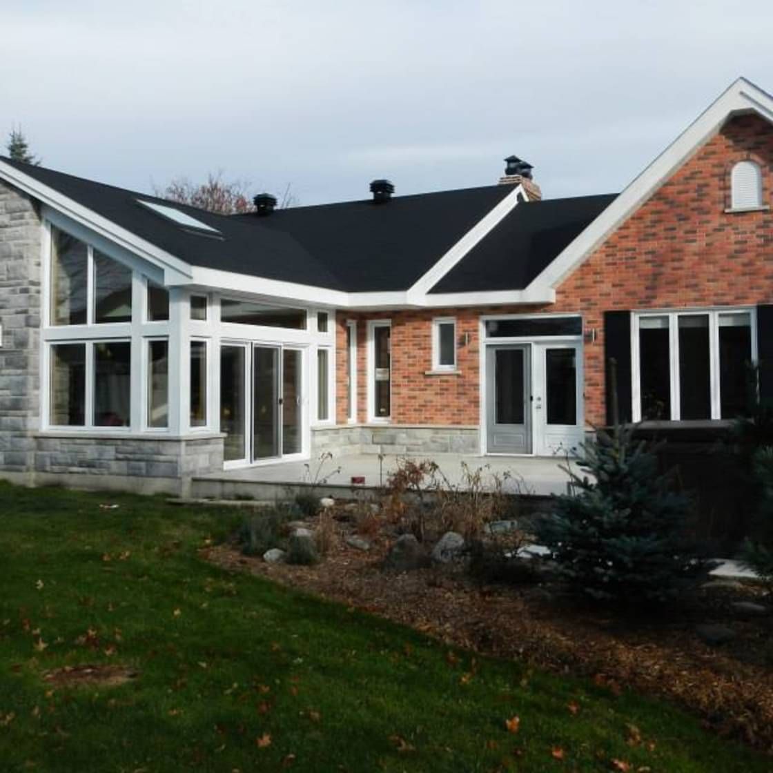 Une maison en briques avec un toit noir et des garnitures blanches