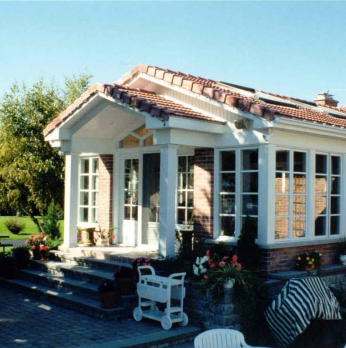 Une maison en briques avec un porche blanc et de nombreuses fenêtres