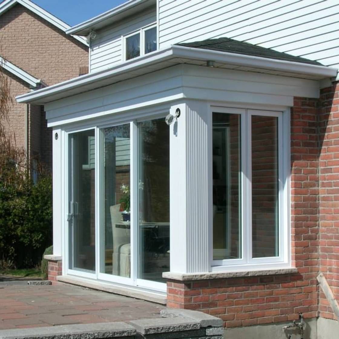 Une maison en briques avec un porche blanc et des portes coulissantes en verre.