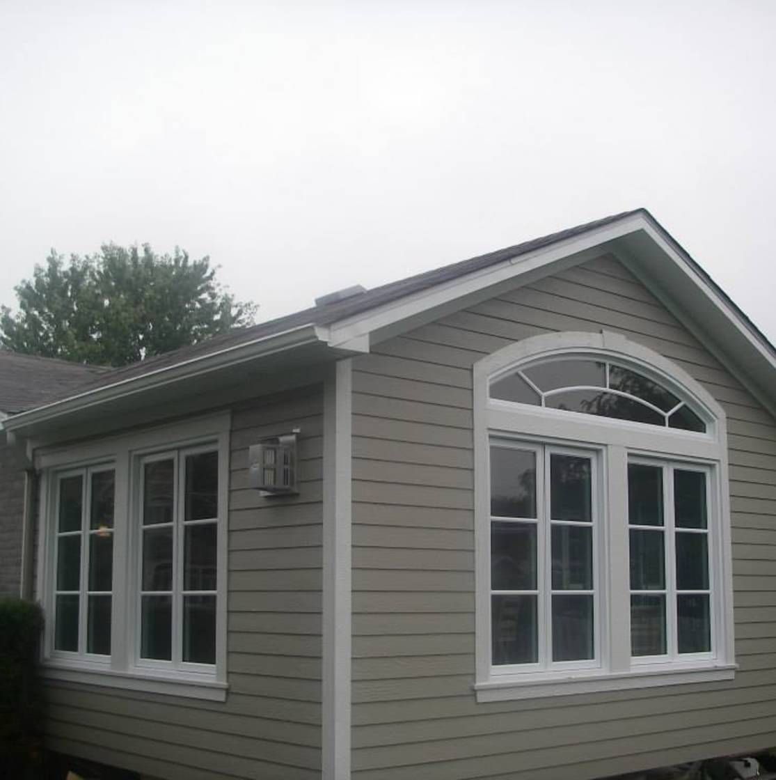 Trois personnes observent une porte de garage exposée dans une salle d'exposition.