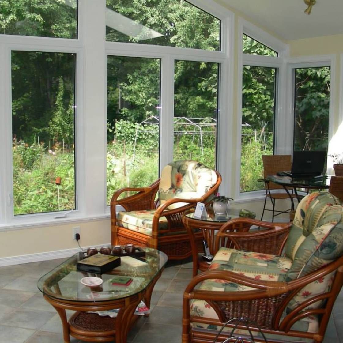 Un salon avec des meubles en osier et de nombreuses fenêtres