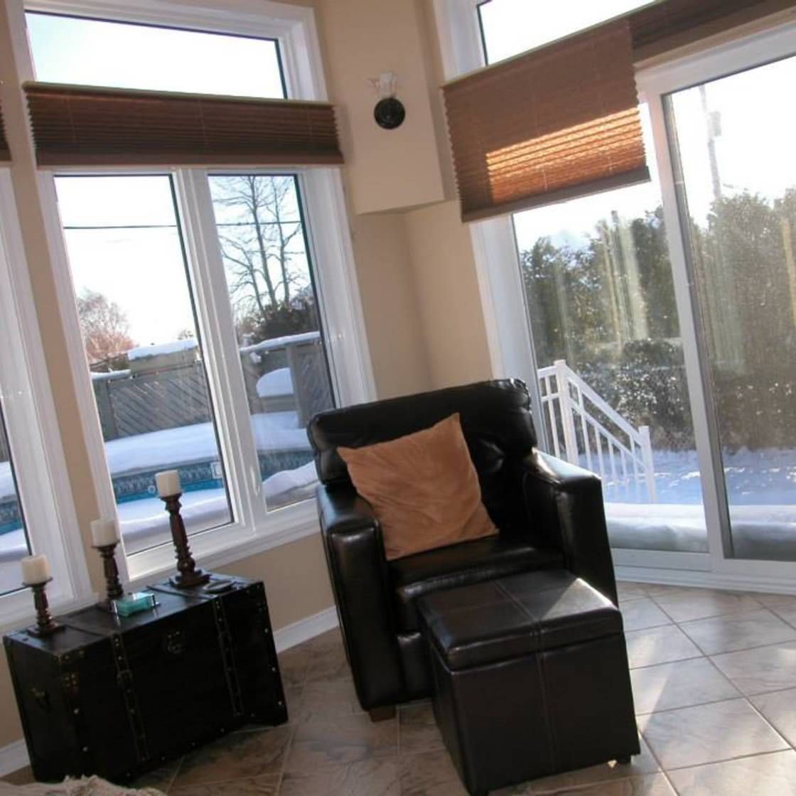 Un salon avec une porte coulissante en verre et une chaise et un pouf