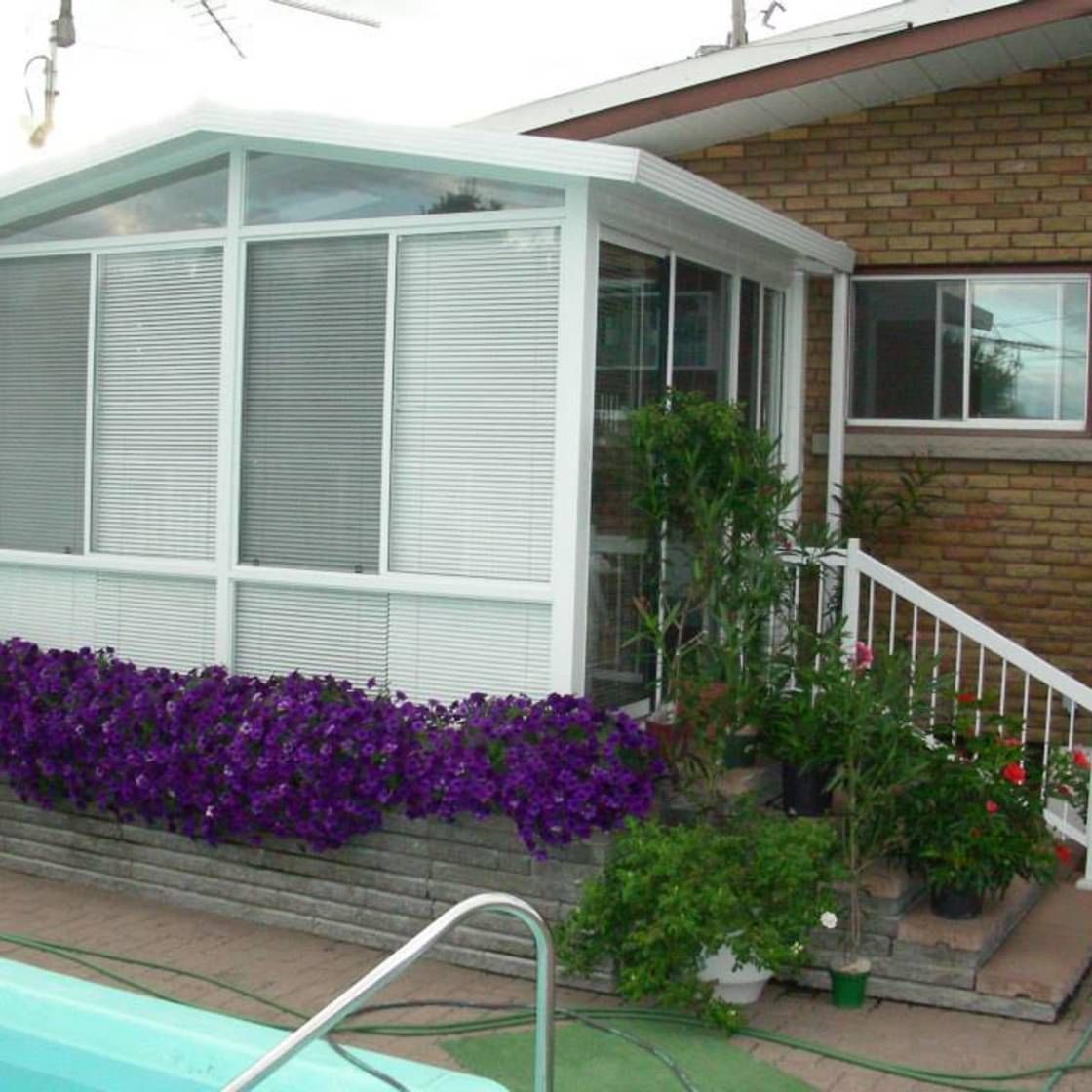 Une maison avec une piscine et des fleurs violettes devant