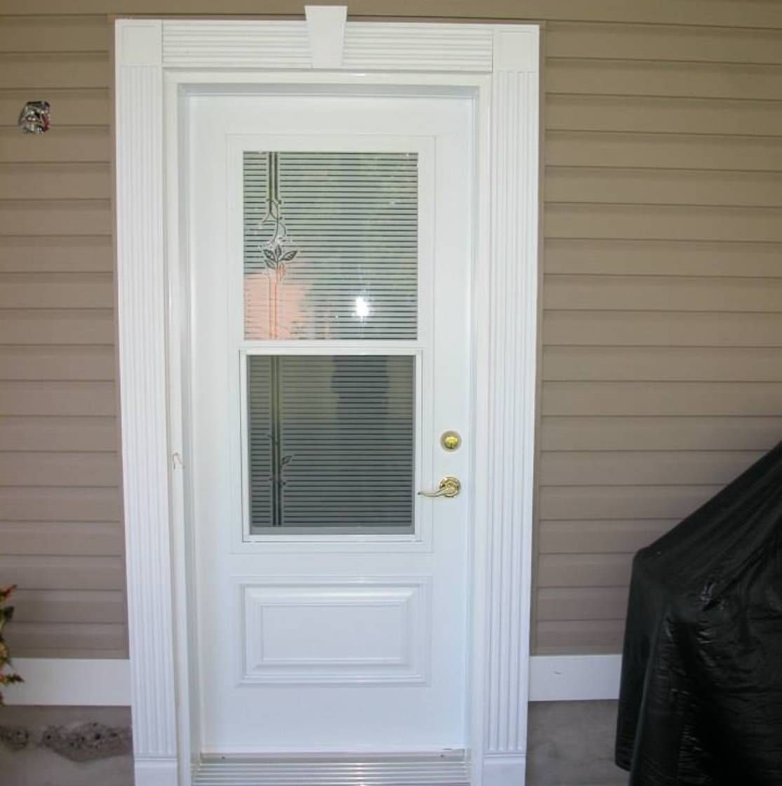Une porte blanche avec une fenêtre et des stores dessus