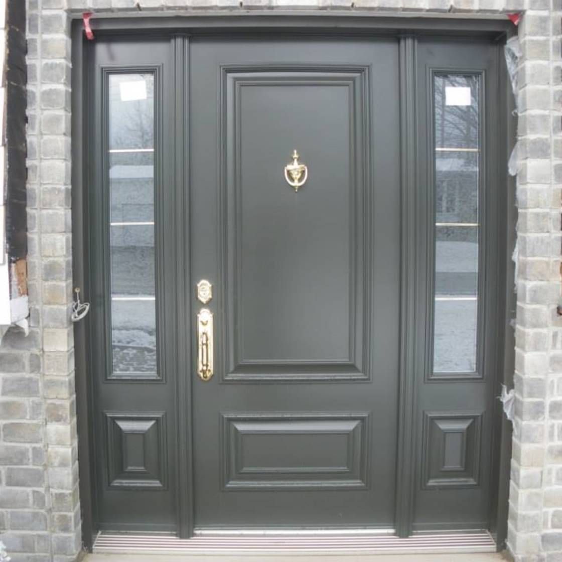 Une porte noire avec un heurtoir doré dessus