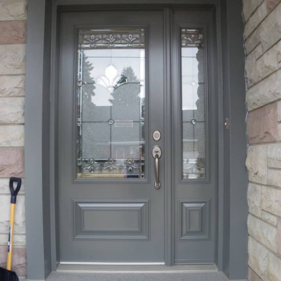 La porte d'entrée d'une maison avec une pelle appuyée contre elle.