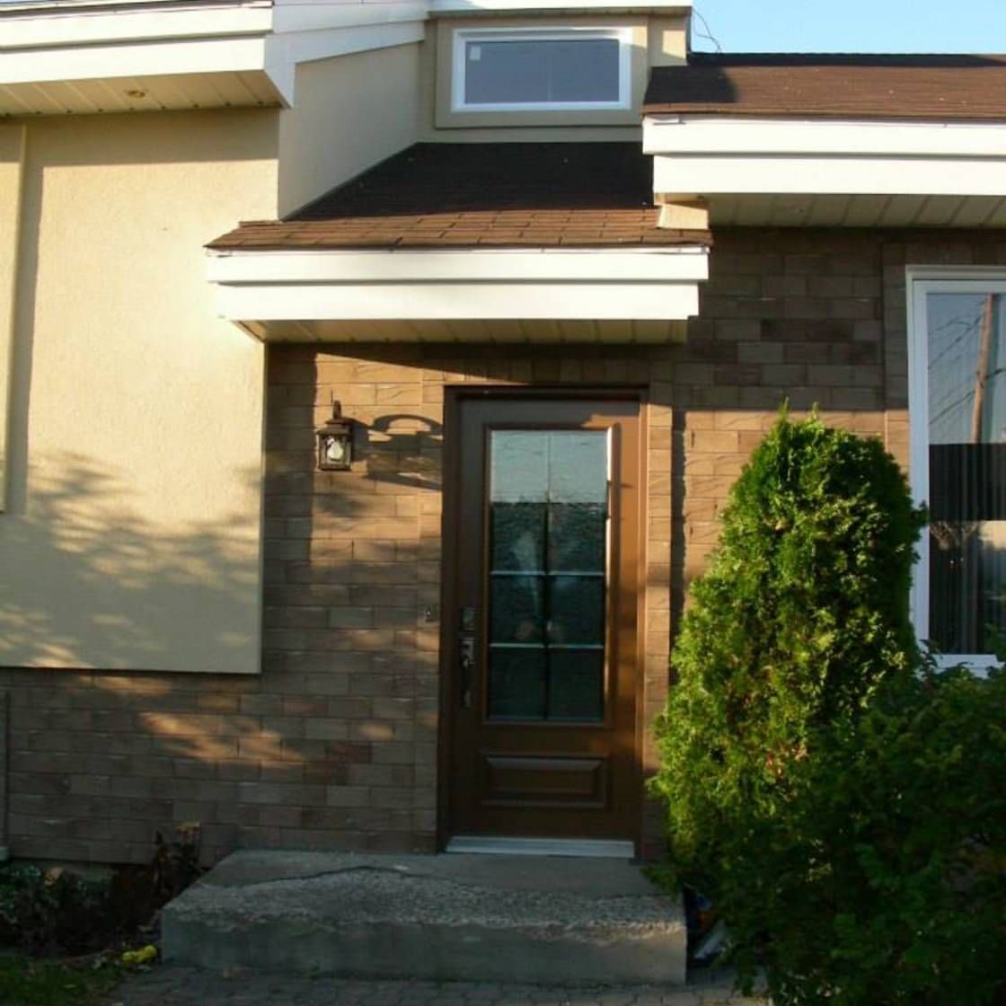 Une maison avec une porte marron et une fenêtre blanche
