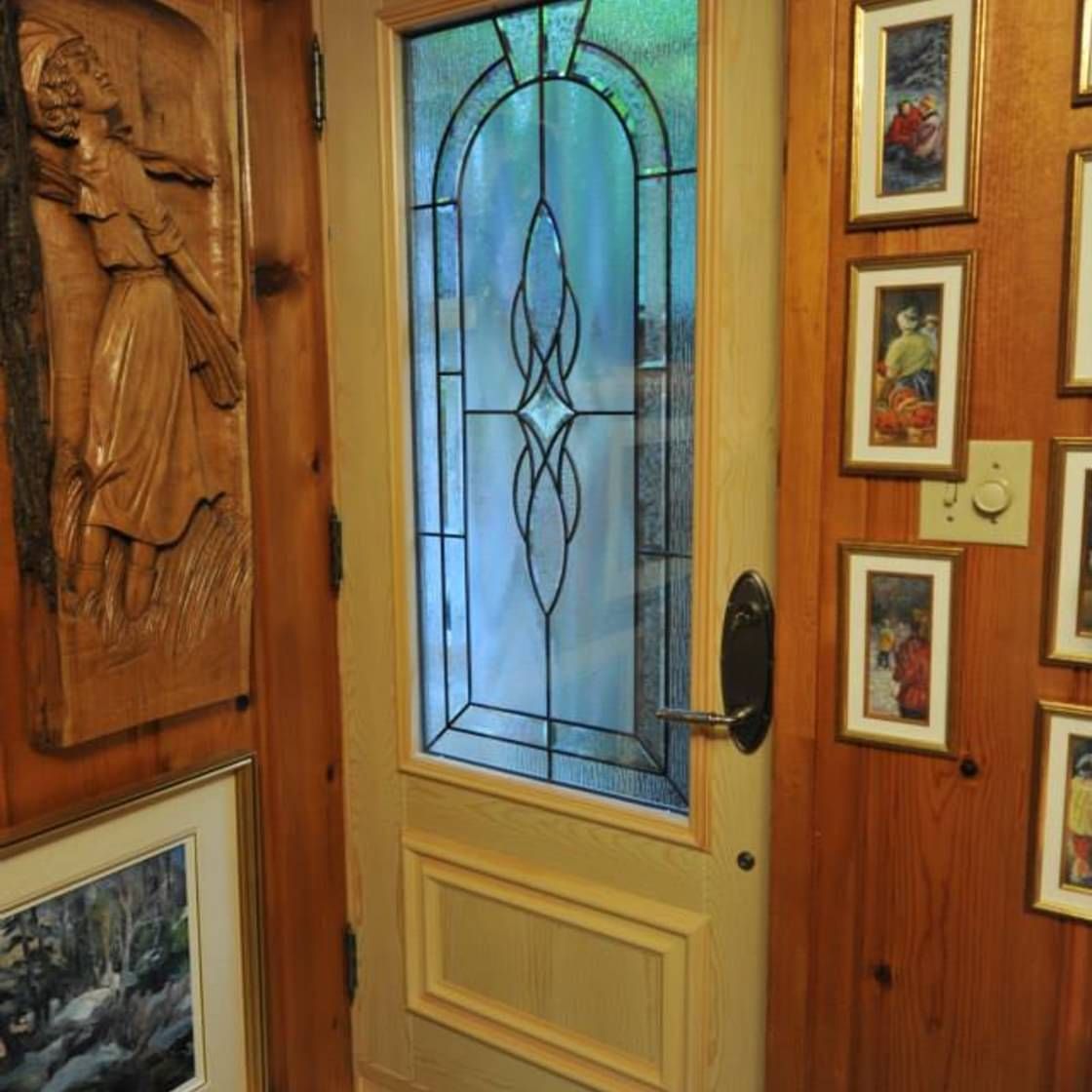 Une porte avec un vitrail est entourée de tableaux sur le mur