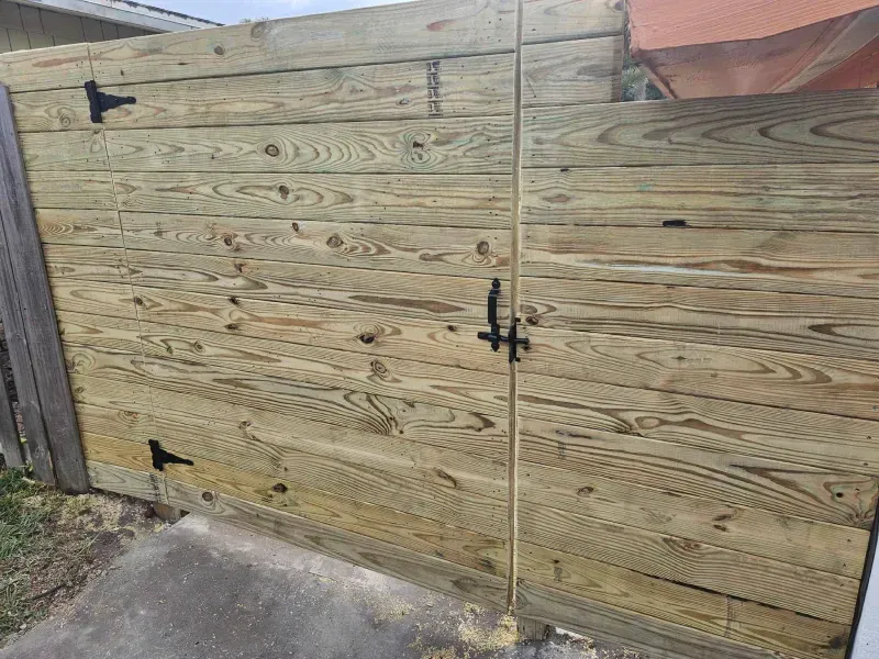Wooden fence with a gate, black hardware, outdoors.