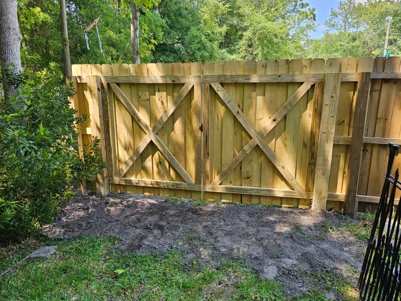 Wooden gate with crisscross design within a wooden fence, outdoors.