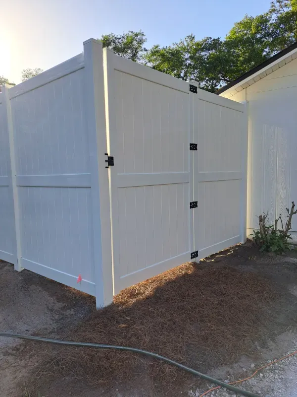 White vinyl privacy fence with black hinges and latch.