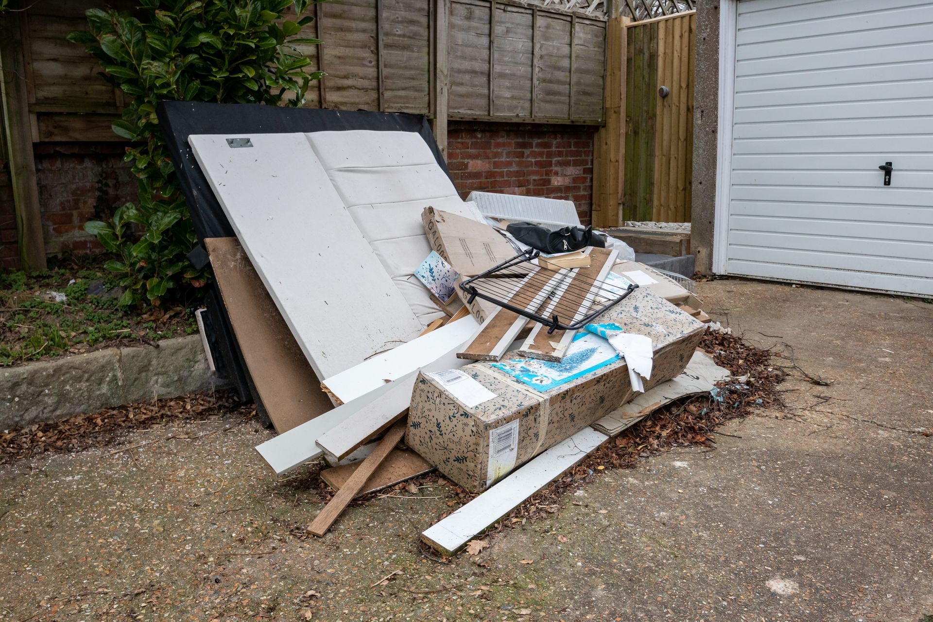 Pile of discarded construction materials and debris near a garage.