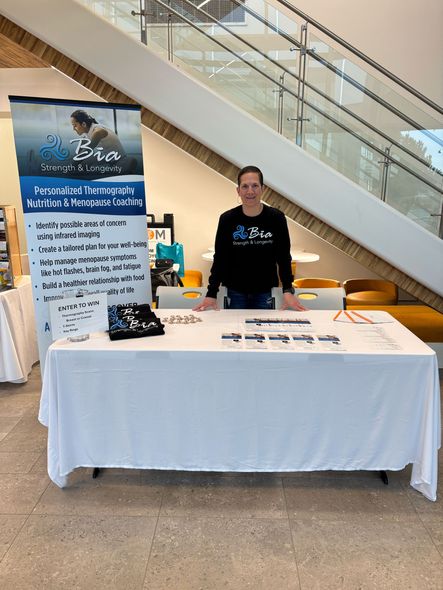 A woman is standing at a table in front of a sign.