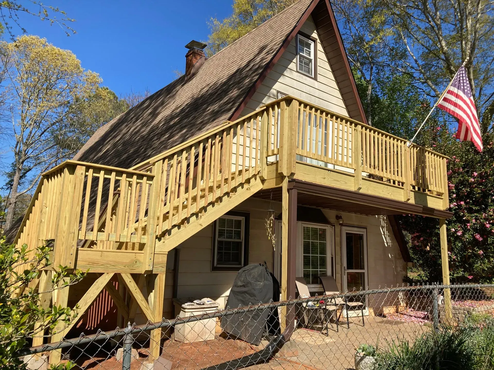 A-frame house with wooden deck and stairs. American flag flies.