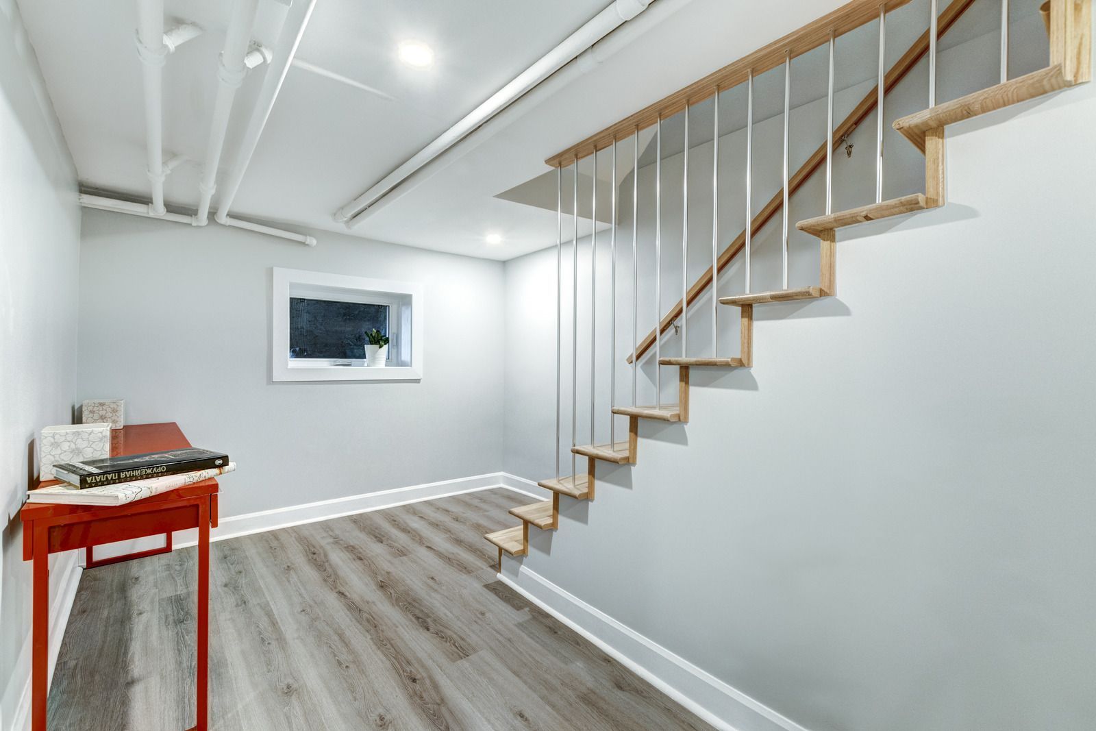 A basement with a wooden staircase and a desk.