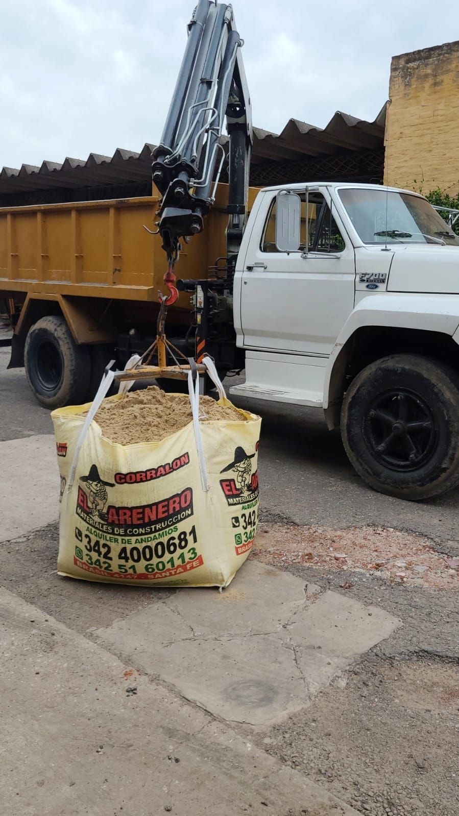 Una gran pila de arena de construcción de color claro yace en un terreno baldío con tierra de color marrón rojizo al fondo.