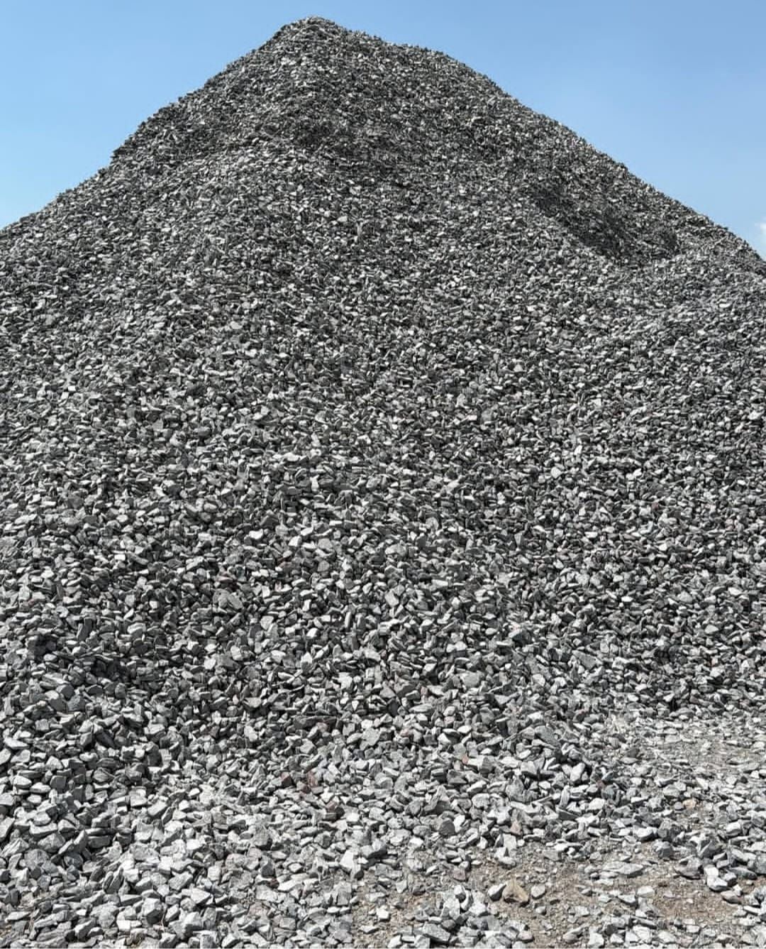 Un gran montón de rocas trituradas de color gris oscuro y blanco, aisladas sobre un fondo blanco.