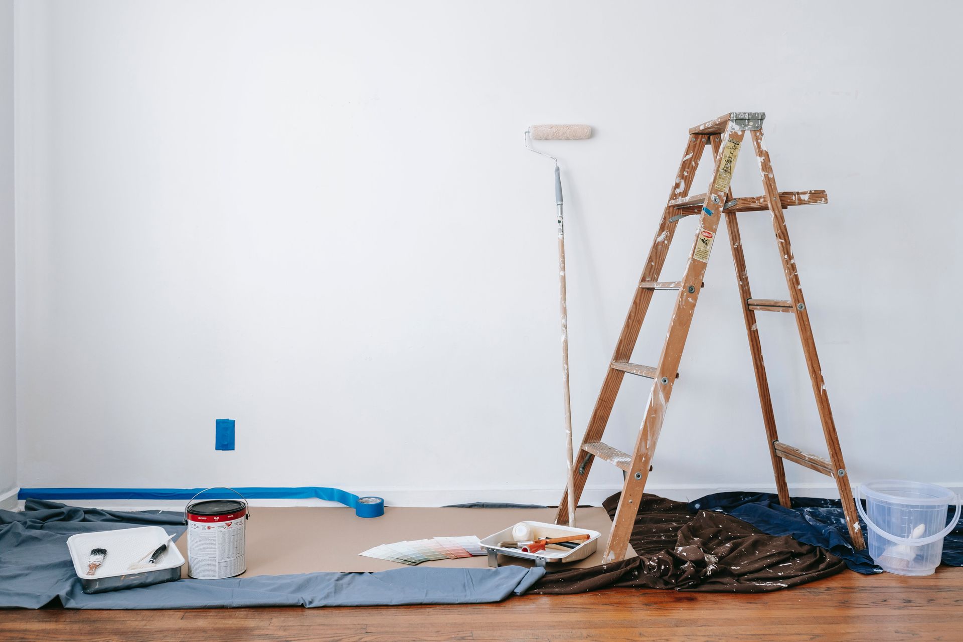 There is a ladder and a paint roller in the room.