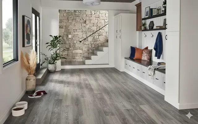 Spacious entryway with gray wood-look flooring, stone accent wall, bench with hooks, and open stairs.