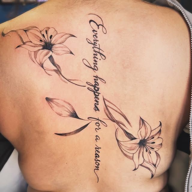 Back tattoo featuring two lily flowers with stems flanking a vertical script reading:
