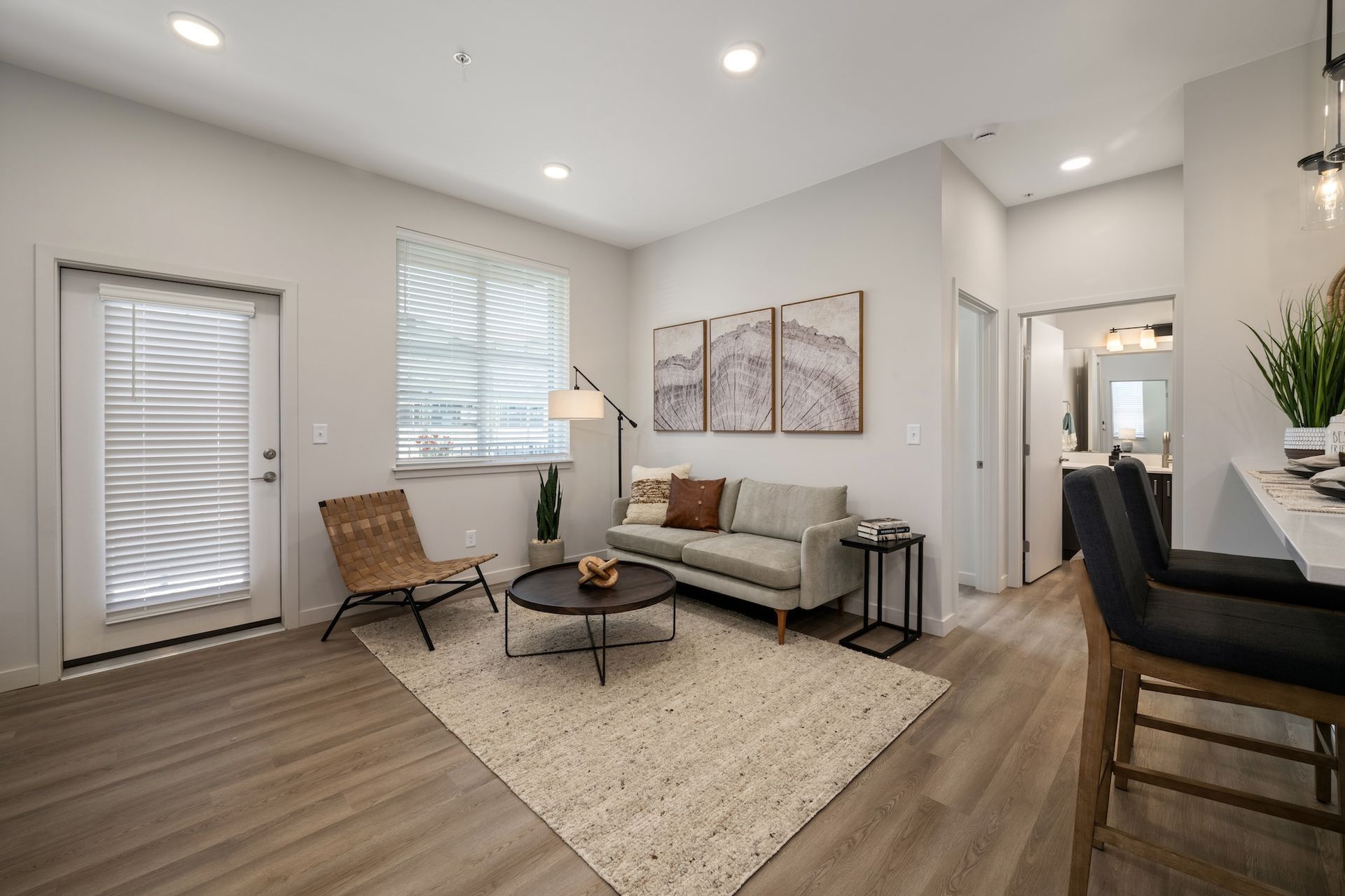 Living room with beige walls, wooden floor, sofa, rug, and doorway.