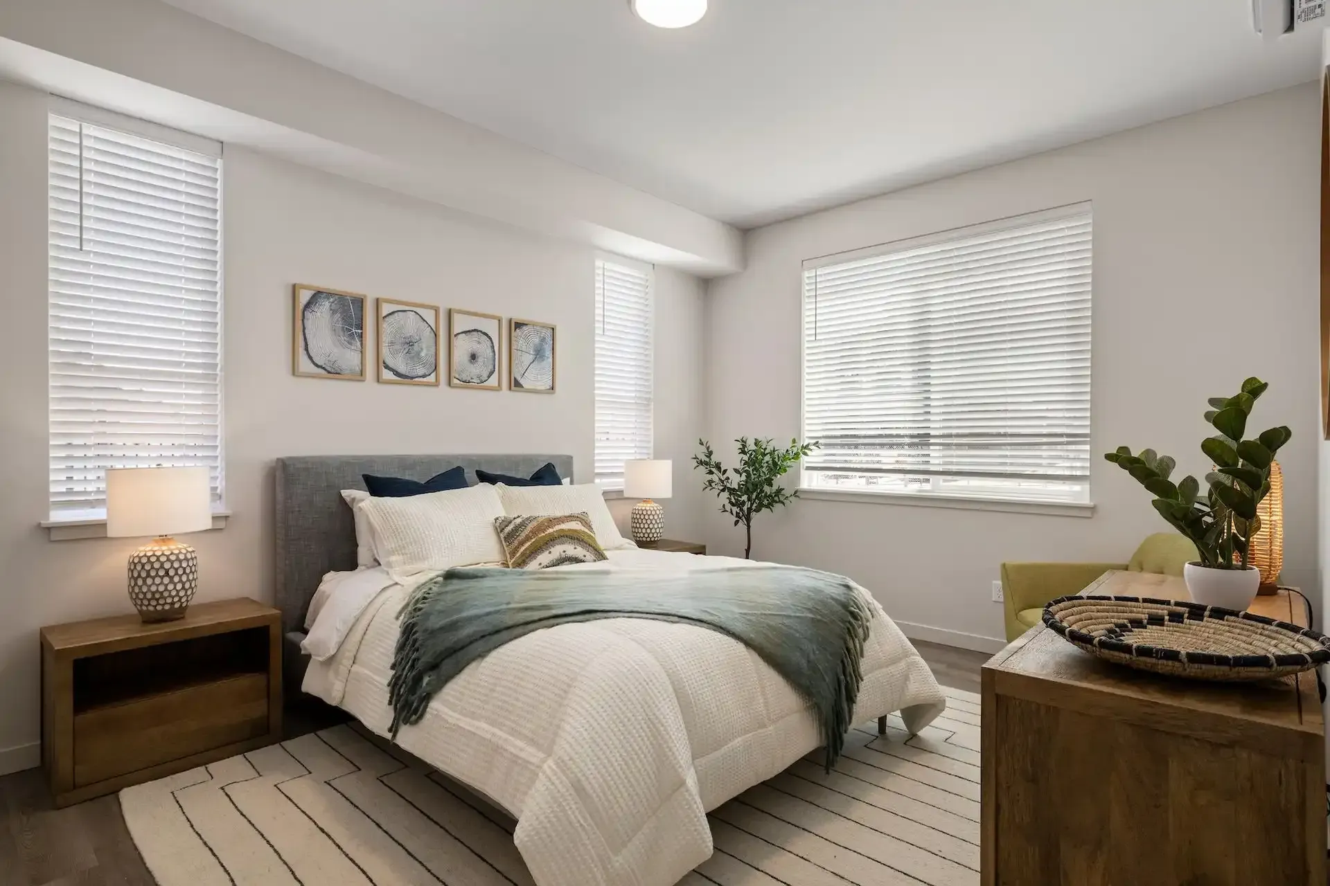 Bedroom with bed, nightstands, windows, artwork, and rug.