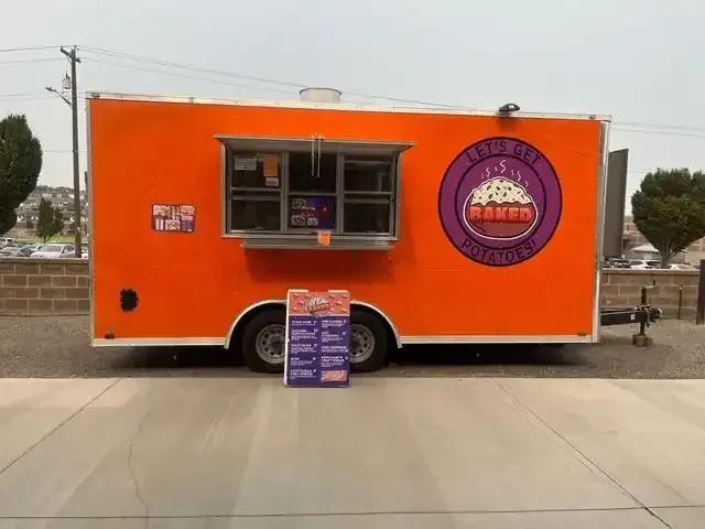 Orange food trailer with purple logo and menu sign.