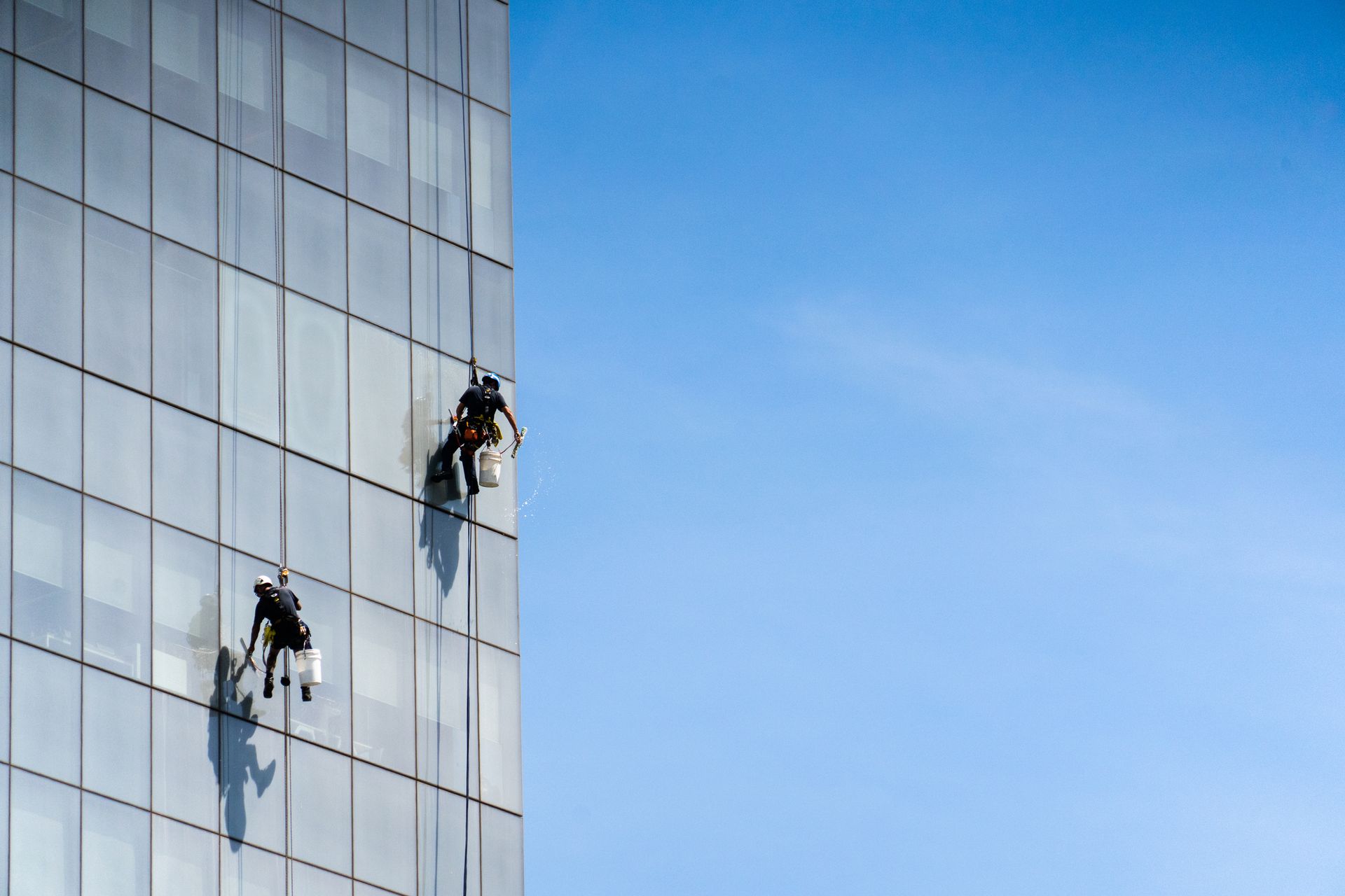 Two men are cleaning the windows of a tall building.