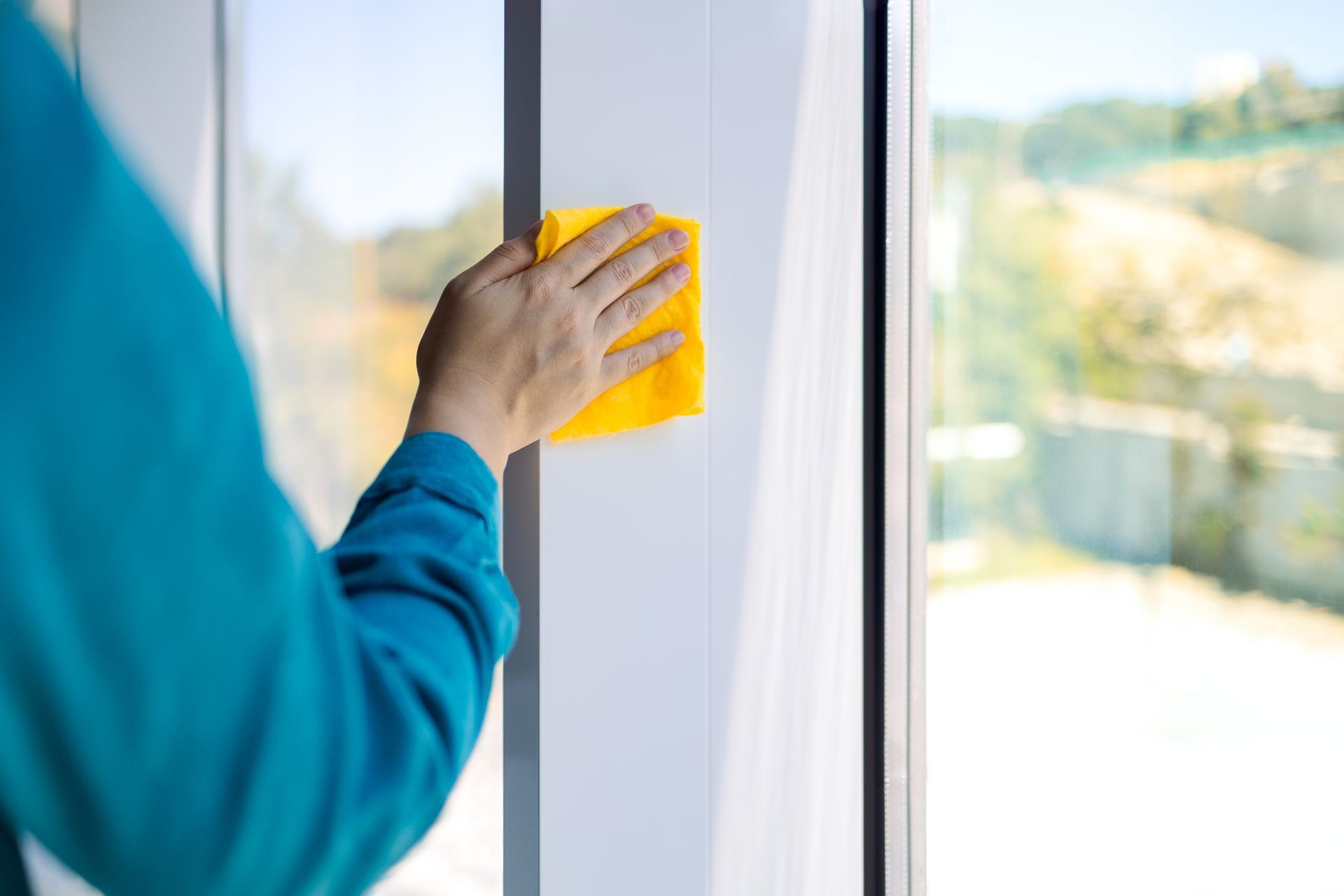 A person is cleaning a window with a yellow cloth.
