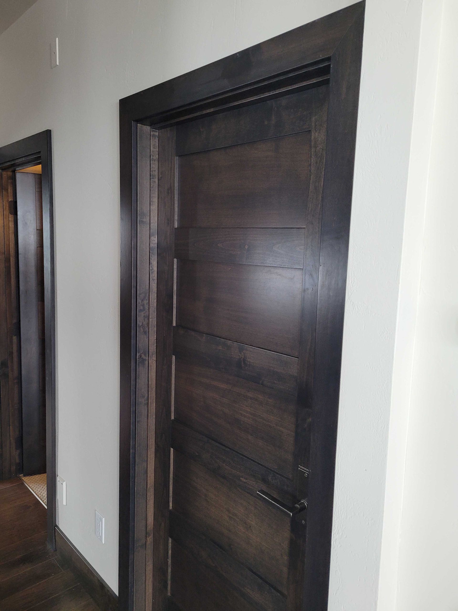 A dark stained horizontal plank door set in a white wall with matching door frame and trim.