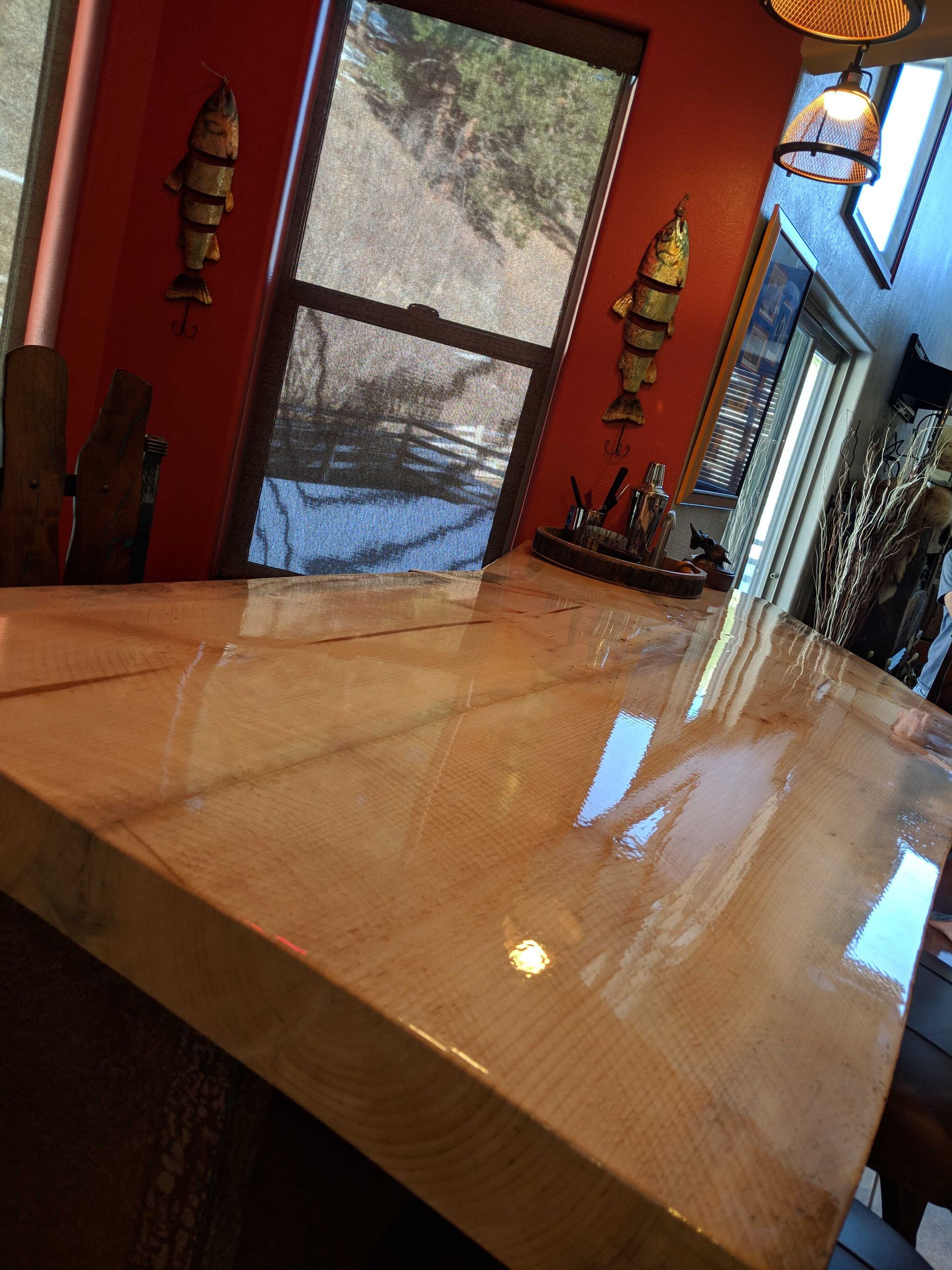 A high-gloss, light-wood countertop in a room with orange walls and decorative fish wall art.