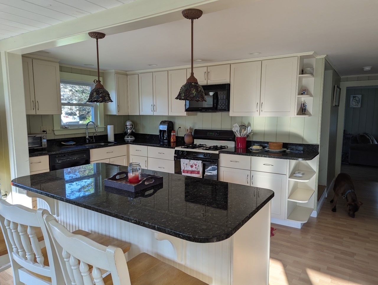 A kitchen with white cabinets and black granite counter tops
