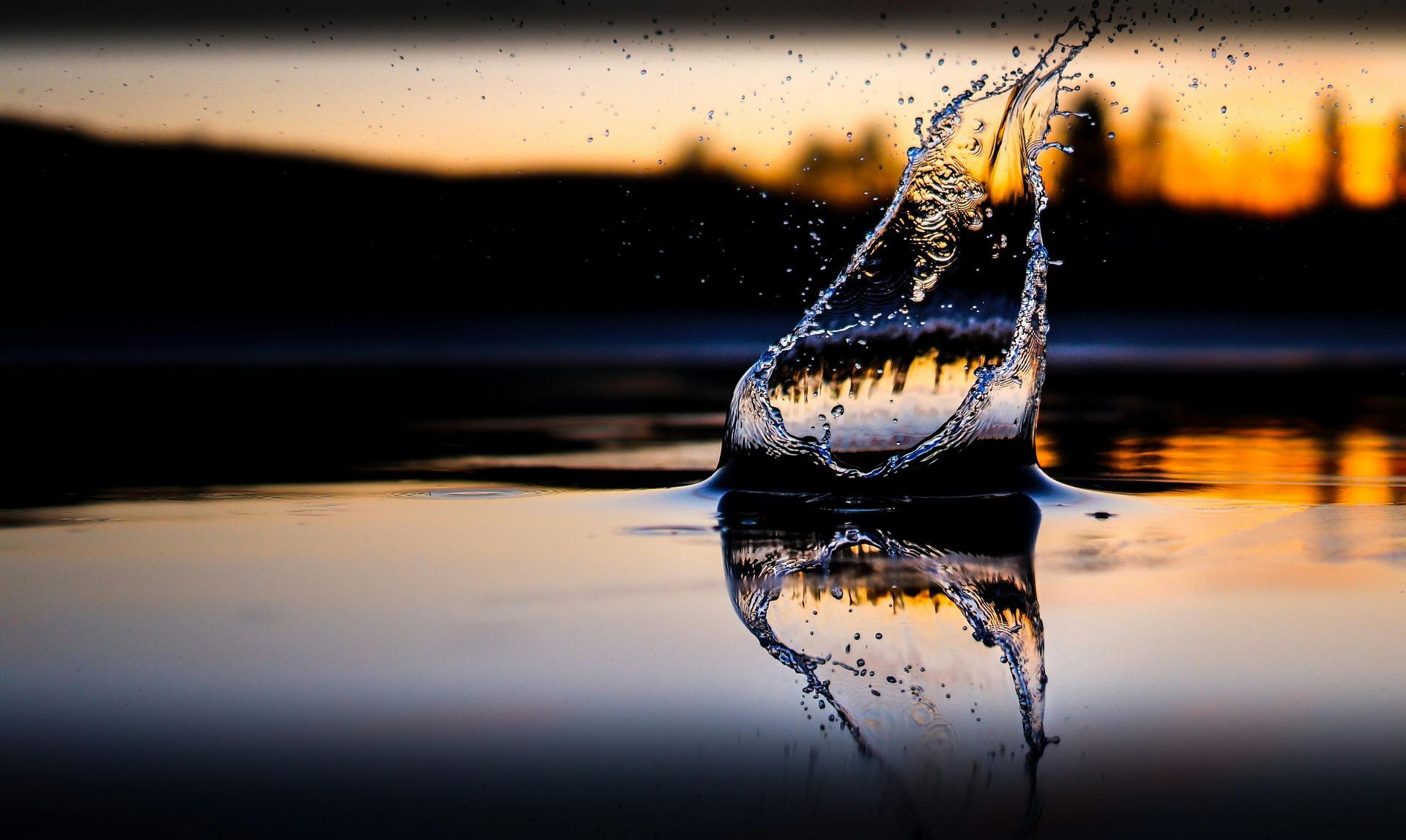 Splash of water on a lake reflecting an orange sunset.