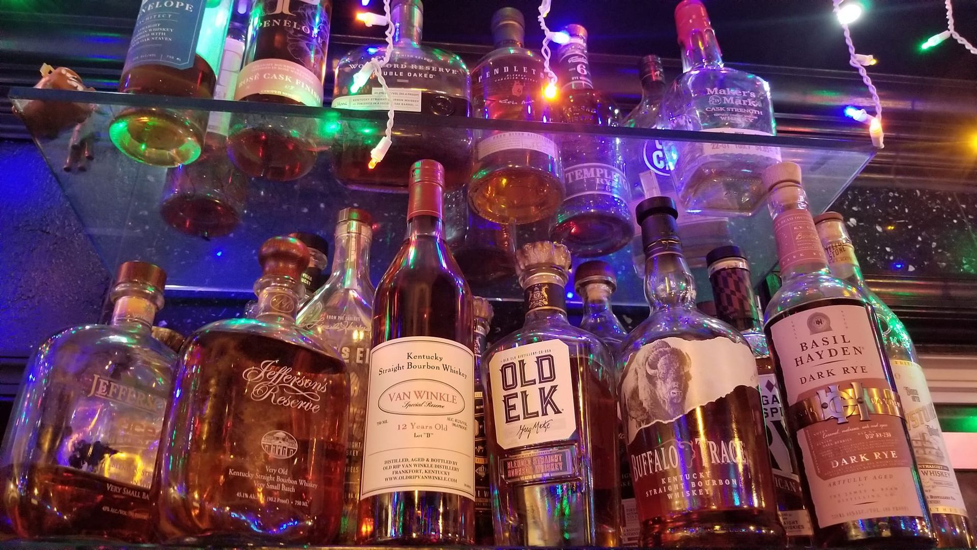 A shelf filled with bottles of alcohol including old elk