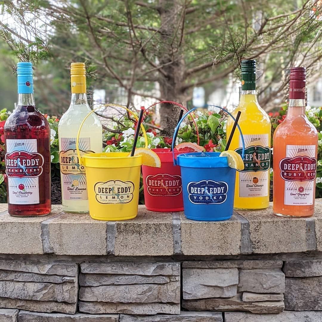 A group of bottles and cups sitting on top of a stone wall.