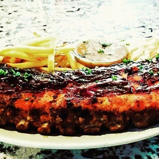 A white plate topped with ribs and french fries