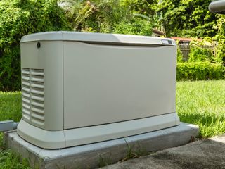 A generator is sitting on top of a concrete block in the grass.