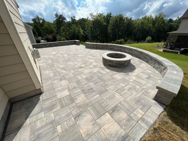 Paver patio with curved stone retaining wall and fire pit.