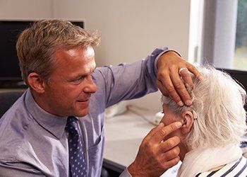 Hearing Healthcare Repairs — Doctor Checking the Hearing Aid Device  in Pottstown, PA