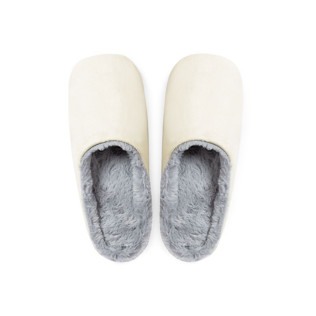 Un par de zapatillas de casa sin cordones de color crema con un suave forro de piel sintética gris, vistas desde arriba sobre un fondo blanco.